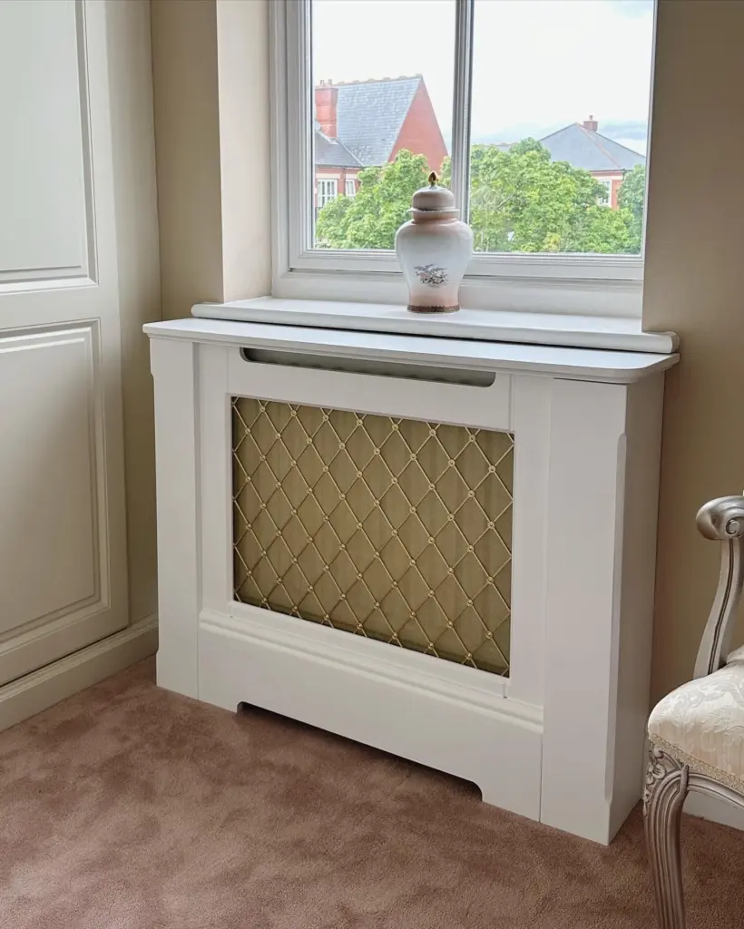 traditional standing radiator cabinet with brass regency grille under small window in luxury home